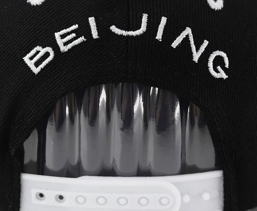 Cotton baseball cap with embroidered letters in black or white, showing adjustable strap and dome crown.