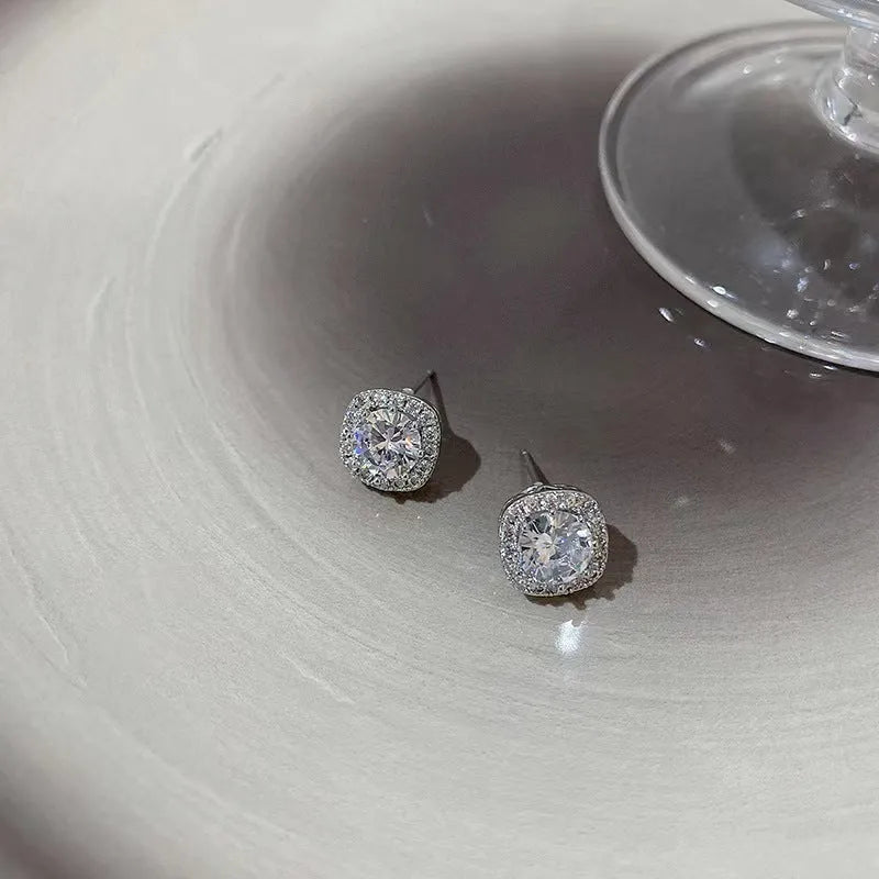 A pair of square geometric diamond-treated alloy earrings on a silver or gold background.