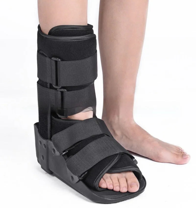 Black Achilles tendon rehabilitation boot with aluminium uprights on a grey background.