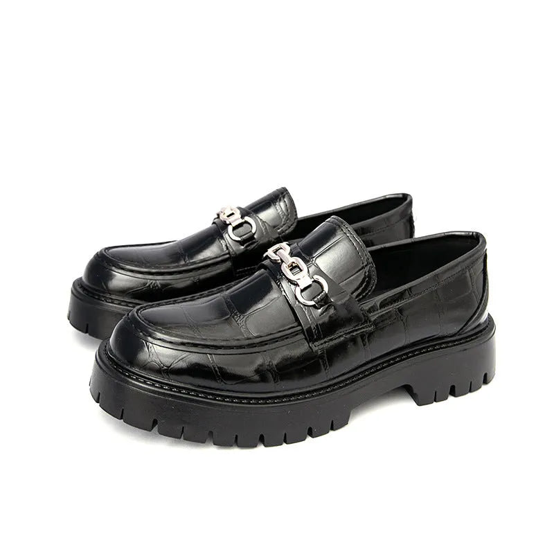 Men's black crocodile pattern loafers with a flat platform sole on a plain background.