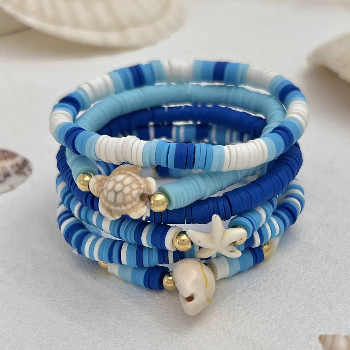 Six Bohemian blue polymer clay bracelets with geometric shell designs arranged as a set