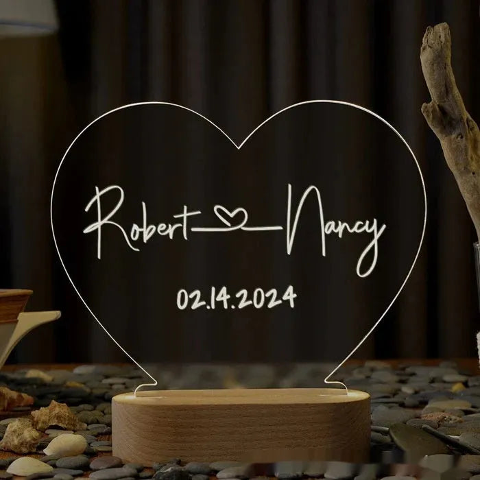 Custom transparent acrylic night light with personalised text, lit by LED, on a bedside table.