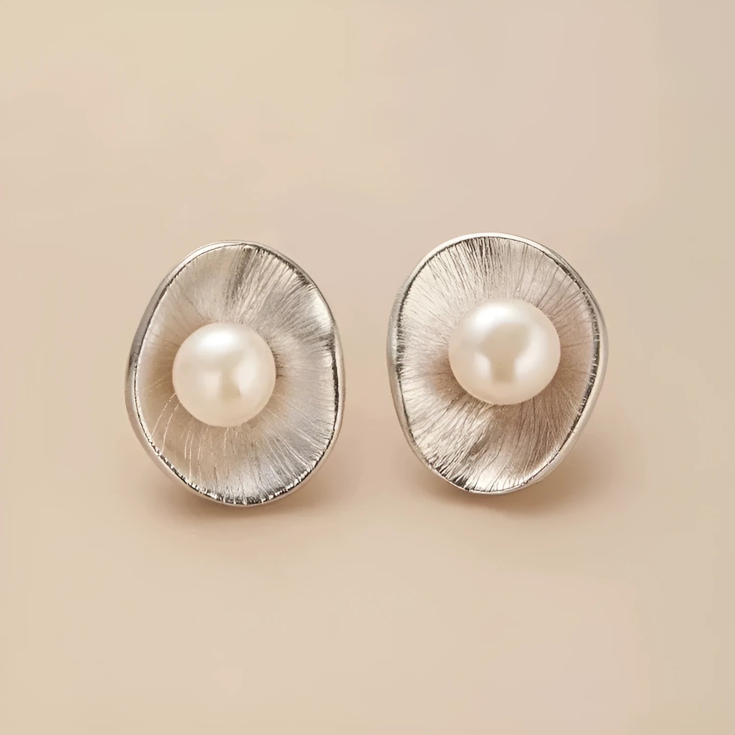 A pair of geometric sterling silver ear studs with pearl accents and a gold electroplated finish.