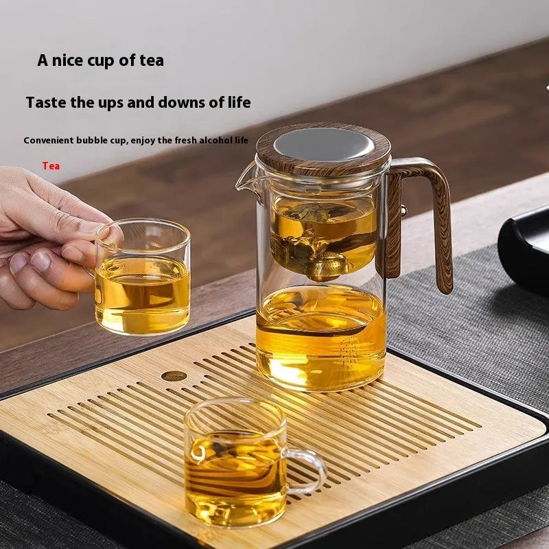 Chinese-style glass teapot with wooden handle showing magnetic filtration button and inner infuser container.