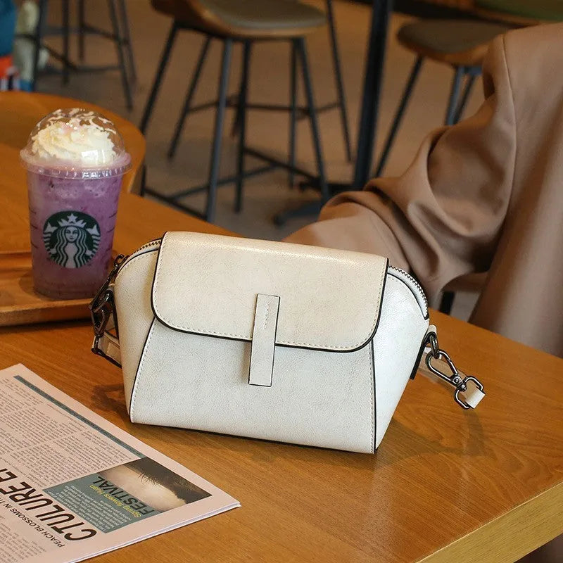 Women's brown oil wax leather shell-shaped messenger bag with a cross-body strap and front sandwich pocket.